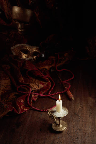 istock Burning candle in an old brass candlestick and carnival masks. 1427680705