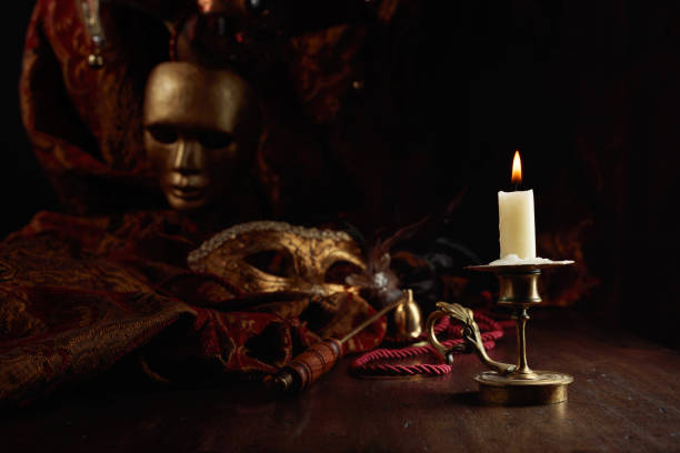 istock Burning candle in an old brass candlestick and carnival masks. 1427680718