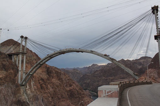 Boulder City, NV, USA - August 23, 2009: Overcast view downstream from Hoover Dam scenic overlook showing Mike O'Callaghan–Pat Tillman Memorial Bridge during construction. Concrete arch has been completed, central bridge deck segments were not yet constructed at time of photo.