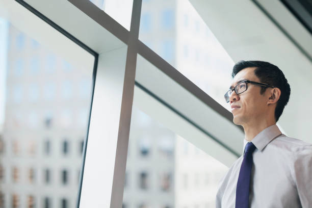 istock Asian businessman standing in office and looking through window at view 1427683076