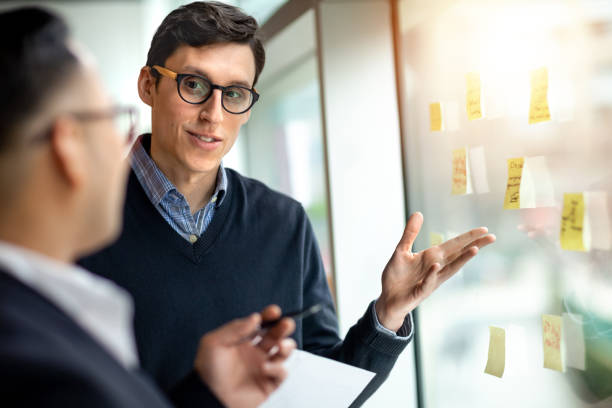 istock Colleagues talking together and pointing to ideas on notes on window in office 1427684312