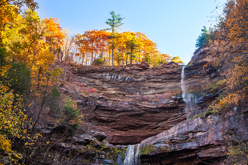 Kaaterskill Falls is the crowning jewel is the highest cascading waterfall in New York State located in the eastern Catskill Mountains between the hamlets of Haines Falls and Palenville in Greene County. The waterfall dropping in two tiers over 260 feet. It is accessible through an excellent moderate hiking trails which afford fabulous views of the fall and the surrounding forest. Autumn Waterfall in mountain with foliage. Colorful autumn, fall. Midday. October 23, 2016. New York Upstate. USA
