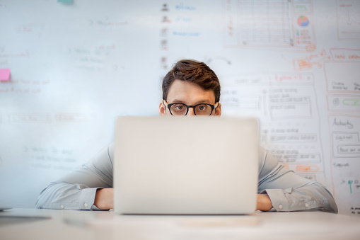 Hombre de negocios mirando la pantalla de la computadora portátil mientras está sentado a la mesa en una oficina creativa photo
