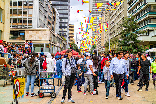 Bogotá, Colombia - August 24, 2019: Looking Northwards on Carrera Séptima downtown Bogotá where the Carrera becomes and pedestrian only zone. People are seen enjoying the street on a Saturday, during the weekend. Colombian national flags from a previous national holiday still adorn the street.