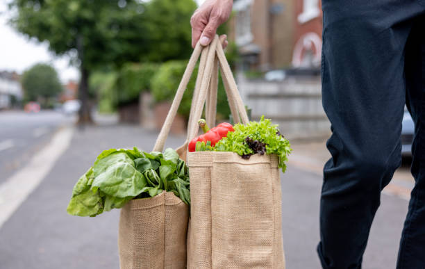 Close-up on a man carrying a shopping bag with groceries on his way home Close-up on a man carrying a shopping bag with groceries on his way home - domestic life concepts reusable bag stock pictures, royalty-free photos & images