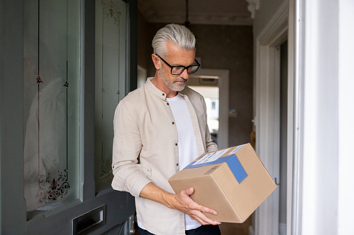 Happy man receiving a package at home â domestic life concepts
