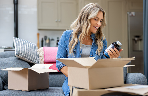 Happy woman opening a package at home after shopping online - e-commerce concepts