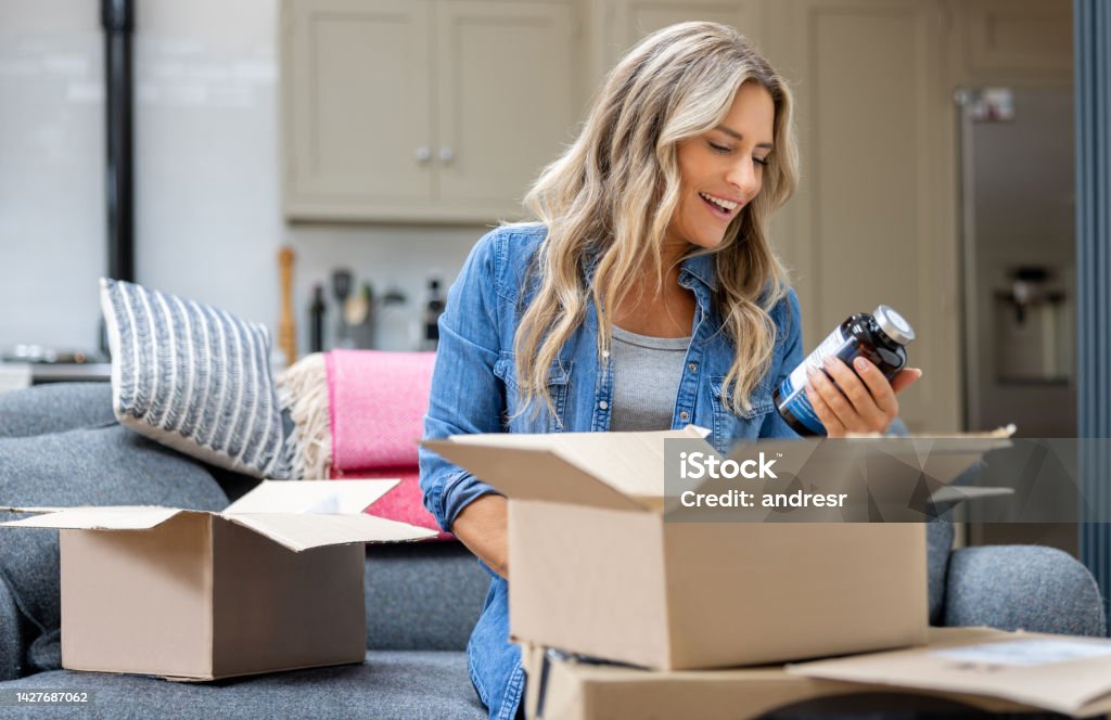 Woman opening a package at home after shopping online Happy woman opening a package at home after shopping online - e-commerce concepts Subscription Stock Photo