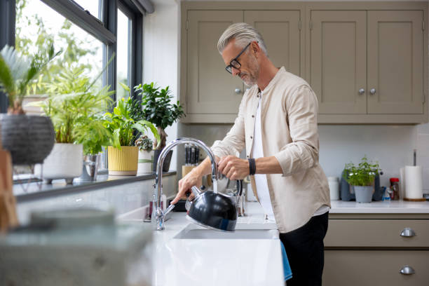 hombre makign una taza de té y poner el hervidor de agua - hervir fotografías e imágenes de stock