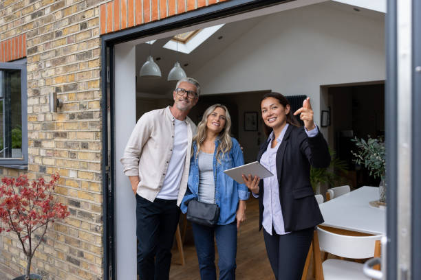 Real estate agent showing a house for sale to a couple Real estate agent showing a house for sale to a couple and pointing outside - home ownership concepts fresh start stock pictures, royalty-free photos & images