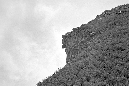 New Hampshire's Old Man of the Mountain..  First discovered by surveyors in 1805, the Old Man quickly became a New Hampshire tourist attraction,  as both local's and visitors alike flocked to Franconia to get a glimpse at the state's Cannon Mountain landmark.  Sometime between May first and May third of 2003, the granite ledges making up the Old Man gave way and collapsed downward leaving only a shear cliff behind.  The image of the Old Man of The Mountain has lived on as New Hampshire's Iconic state emblem, appearing on highway signs, drivers licenses, license plates, and on the reverse of the state quarter.
