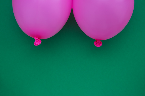 Breast cancer concept without people. Pink balloons on green background. Studio shoot.