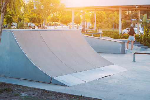 Ramps and halfpipe eqipment and trampolines at the modern urban extreme skate park during sunset time. City sports spaces for teenagers and youth