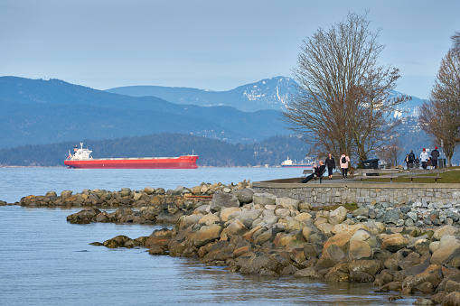 People stroll and relax on the English Bay seawall in downtown Vancouver. British Columbia, Canada. March 16, 2019.