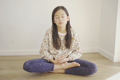 Young preteen girl barefoot practicing yoga and meditating, mindfulness, positive mental health concept