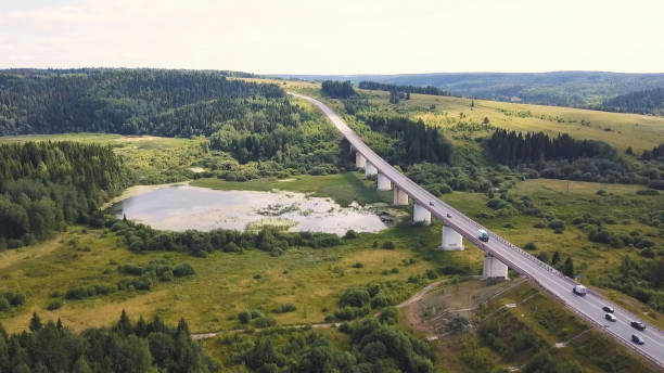 luftaufnahme des autos, das auf der landstraße durch den wald fährt. cip. autos fahren durch waldstraße drone travel countryside adventure. luftaufnahme, die über alte, geflickte zweispurige forststraße mit einem auto fliegt, das grüne bäume bewegt - italian lake district stock-fotos und bilder