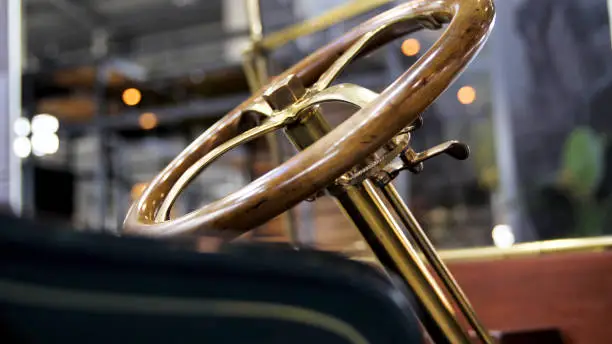 Close up of classic car details at the exhibition. Retro cabriolet car and the golden steering mechanism with a wooden polished wheel.