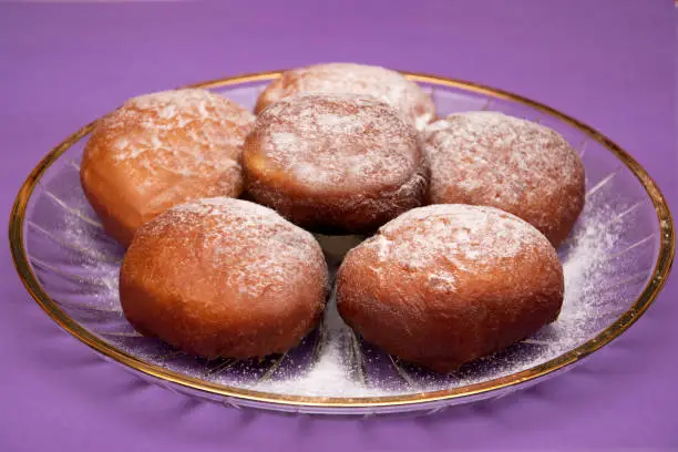 Photo of Donuts on a decorative plate on colorful background. Fat Thursday.