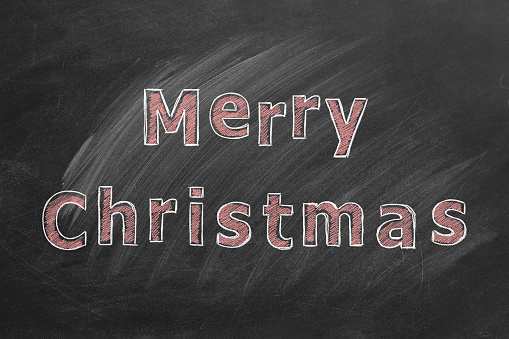 Hand drawn text MERRY CHRISTMAS on blackboard.