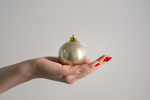 Hand of unknown caucasian woman hold Christmas decoration in hand in front of white background copy space new year celebration concept