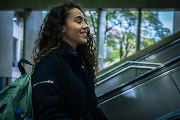 A young woman walking up the subway escalators