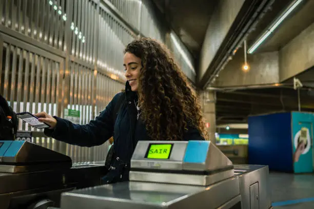 A woman entering the subway station with a QR code ticket on her cellphone