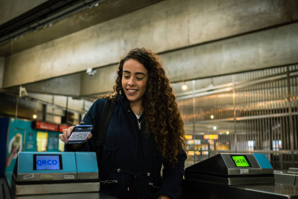 una donna che entra nella stazione della metropolitana con un biglietto con codice qr sul suo cellulare - door tickets foto e immagini stock