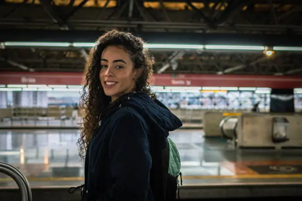 Curly hair woman looking at camera in a subway station