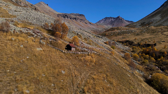 Aerial view of a small house located in mountains, north eastern Italy. Alps mountains in early autumn, beautiful natural place, concept of ecology and loneliness.
