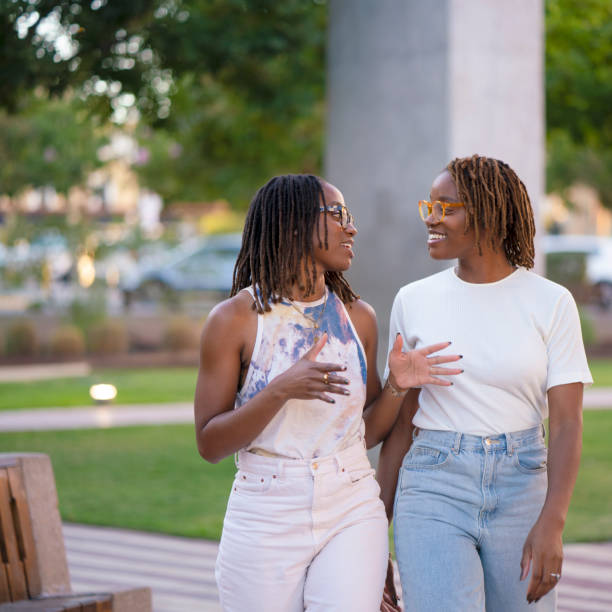 istock Black twin sisters walking and talking in a public park 1427716189