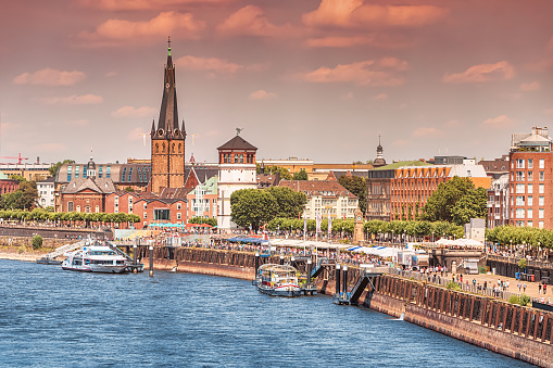 Recognizable architectural towers of the city of Dusseldorf and transportation waterway of the whole of Germany - Rhine River, along which large barges and small ships and boats scurry.