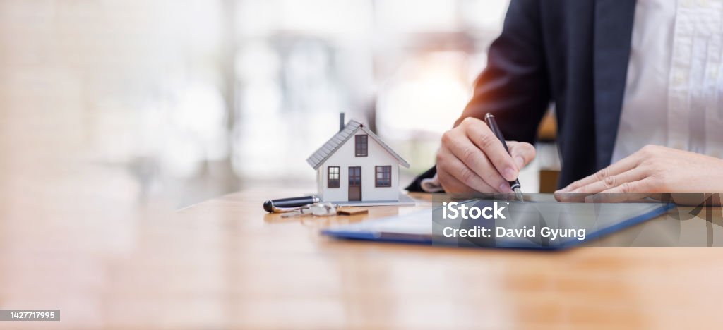 house model with business man signs a purchase contract or mortgage for a buy and sell home insurance concerning mortgage loan Real estate concept, copy space for Editor's text. Mortgage Loan Stock Photo