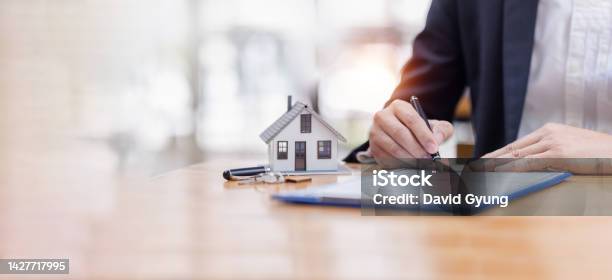 House Model With Business Man Signs A Purchase Contract Or Mortgage For A Buy And Sell Home Insurance Concerning Mortgage Loan Real Estate Concept Copy Space For Editors Text Stock Photo - Download Image Now