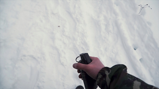 The soldier holds in his hand a training grenade while passing military exercises in the army, snow background. A soldier in camouflage holding a fragmentation grenade in slow motion.