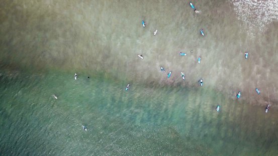 An aerial view of surfers waiting for a wave in the ocean on a clear day. Aerial view of surfer on huge Indian ocean wave. Surfers on the beach top view.