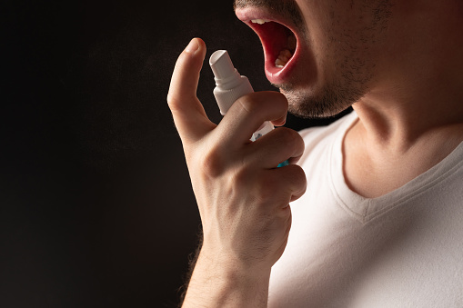 Healing pain in throat theme. Man spray his mouth