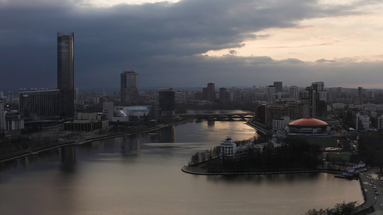 Panorama of the pond and Yekaterinburg Iset skyscraper. Aerial view of Dinamo building with round orange roof and the modern cityscape.
