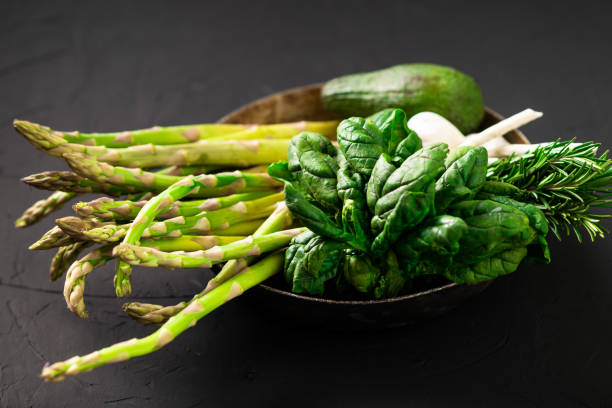 istock Various green vegetables on a dark background. Asparagus, spinach, avocado, garlic. Vegetarian food concept. 1427726243