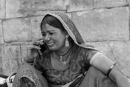 Jaisalmer, Rajasthan, India - October 13, 2019 : Rajasthani woman smiling while talking in mobile phone in market place Inside Jaisalmer Fort. Happy woman of Jaisalmer.