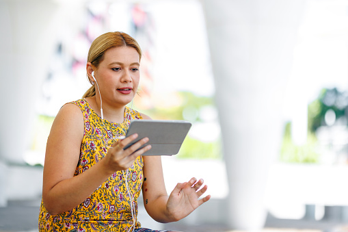 Aboriginal Australian woman studying online in the park in her own time on digital tablet