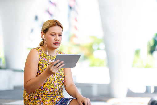 Aboriginal Australian woman studying online in the park in her own time on digital tablet