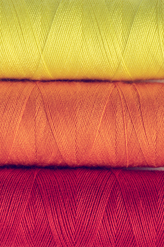 Colorful sewing thread spools close up. Full frame background, top view.