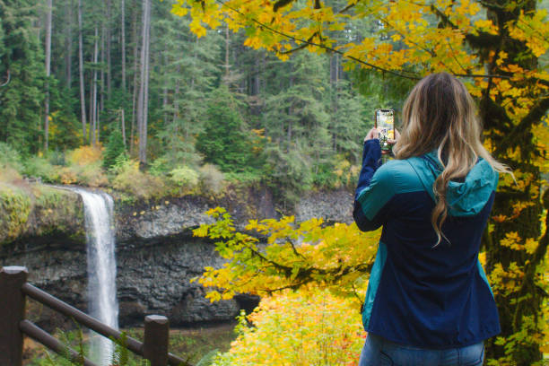 Woman Photographing a Waterfall on Vacation in Oregon stock photo