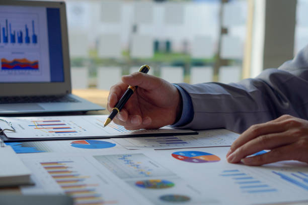 istock Businessman holding pen pointing to graph while analyzing financial paper graph and on desk at office 1427797184