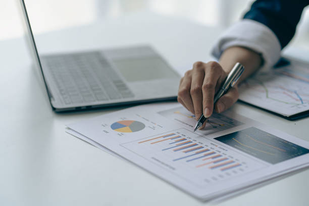 istock Businessman holding pen pointing to graph while analyzing financial paper graph and on desk at office 1427797301