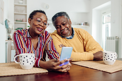 African American senior couple using a smartphone at home.