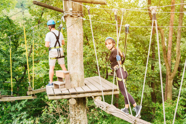 istock High altitude climbing training on adventure track, equipped with safety straps and protective helmet. Summer fun and sports for adventurous people.Adventure climbing high wire park people on course in mountain helmet and safety equipment. 1427804080