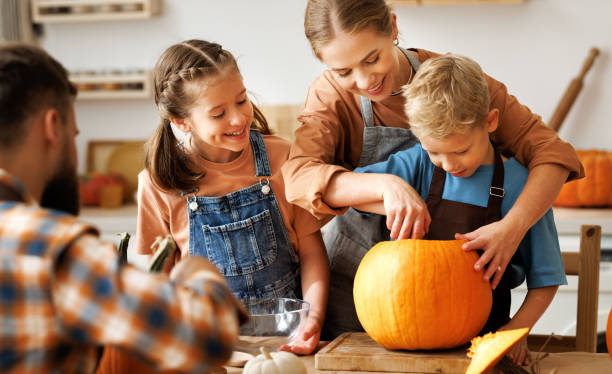 heureux père de famille, père et enfants pour enlever la pulpe de la citrouille tout en sculptant jack o lantern avec la famille - citrouille d'halloween enfants photos et images de collection