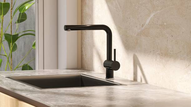 Minimal and contemporary kitchen counter with granite top and stainless sink with sunlight from window on marble wall