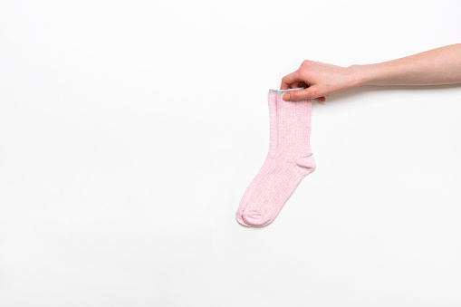 istock Mano femenina sosteniendo un par de calcetines de algodón de mujer modernos de color rosa sobre fondo blanco. Tienda de calcetines de moda. Compra de calcetines, venta, mercancía, concepto de publicidad 1427836878